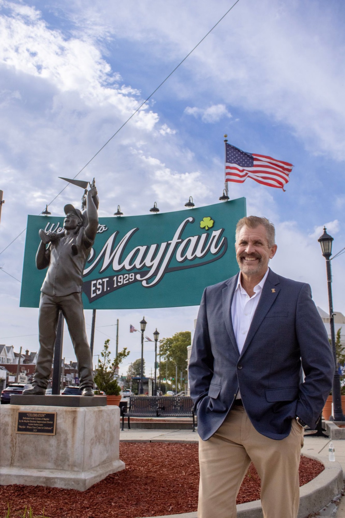 Bill Griffin smiling in front of the Welcome to Mayfair sign in Northeast Philadelphia